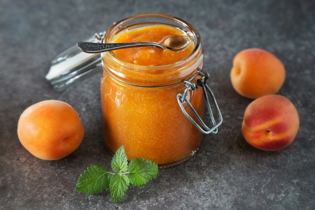 Bocal de confiture d'abricot posé à côté d'abricots frais