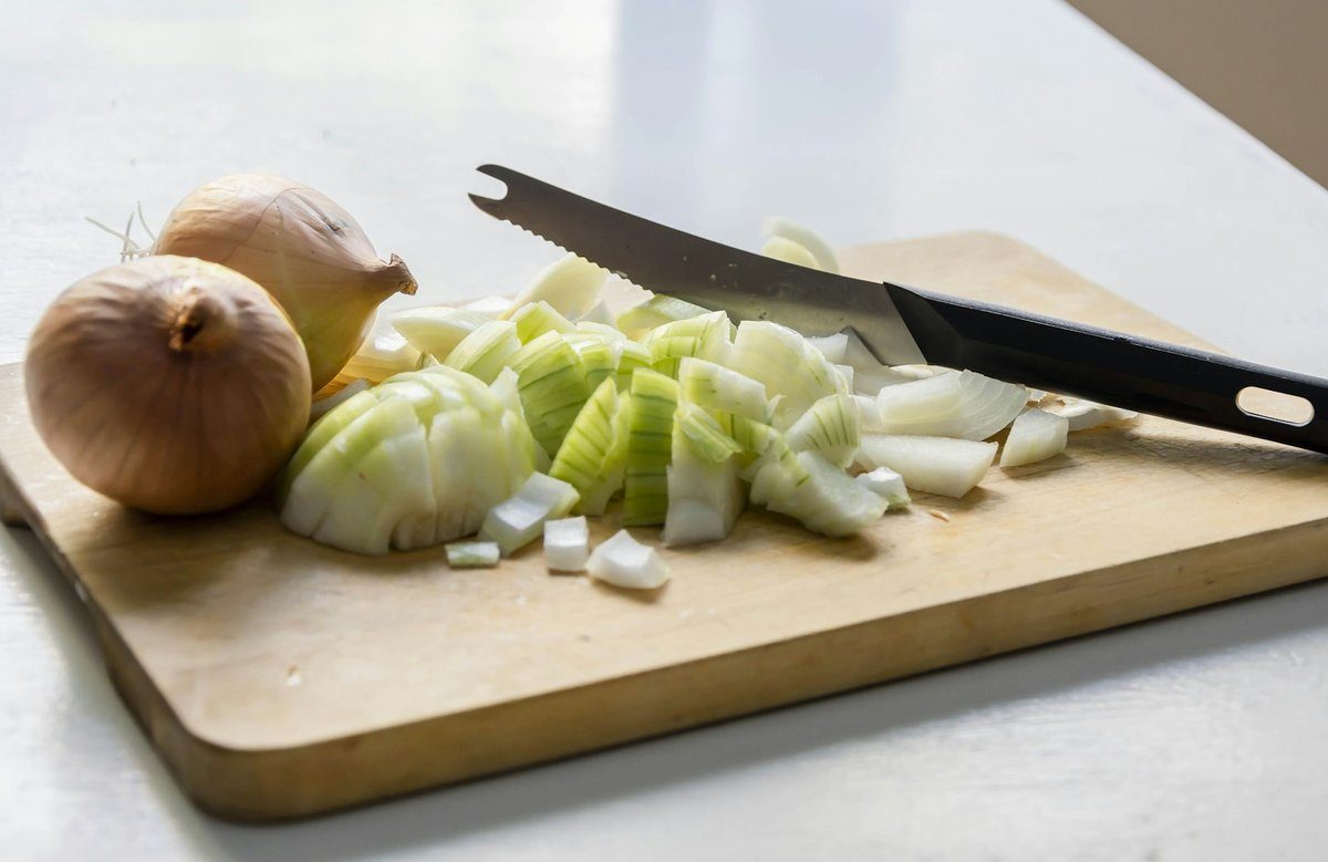 Oignon émincé et couteau posés sur une planche en bois